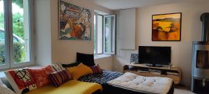uma sala de estar com um sofá e uma televisão em Au petit jasmin em Saint-Puy