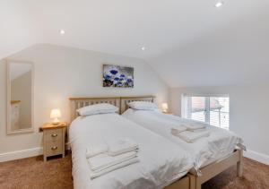 a bedroom with a bed with white sheets and a mirror at Lillie Cottage in Brisley