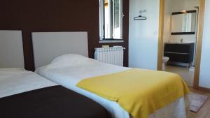 sypialnia z 2 łóżkami i żółtym kocem w obiekcie Casa do Viso w mieście Oliveira do Hospital