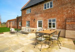 a patio with a table and chairs and a brick building at Manor Farm in Brampton