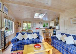 a living room with blue couches and a kitchen at Milliners Lodge in Kelling