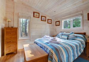 a bedroom with a bed and a wooden wall at Milliners Lodge in Kelling