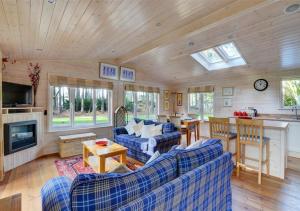 a living room with blue couches and a kitchen at Milliners Lodge in Kelling