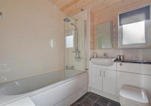 a bathroom with a tub and a sink and a toilet at Milliners Lodge in Kelling +23 photos