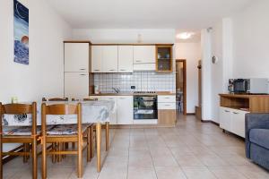 a kitchen with white cabinets and a table and chairs at Appartamento Assenza 9 in Brenzone sul Garda