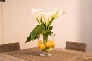 Sunset home Baia Blu في غالّيبولي: مزهرية مع الزهور والليمون على طاولة
