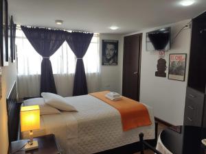 een slaapkamer met een bed, een lamp en een raam bij Hotel el Che No apto para corruptos in Azogues