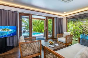 uma sala de estar com uma televisão e uma mesa e cadeiras em Kandolhu Maldives em Himandhoo 