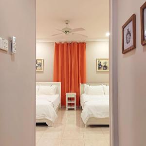 um quarto com 2 camas e uma cortina laranja em My Excel Garden Deluxe Villa with Orchard and Pool em Air Hangat