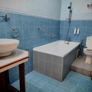 uma casa de banho com azulejos azuis, uma banheira e um WC. em My Excel Garden Deluxe Villa with Orchard and Pool em Air Hangat