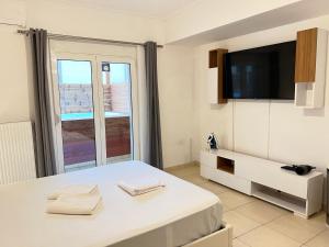 um quarto branco com uma cama e uma televisão em Jacuzzi studio close to athens airport!! em Pallíni