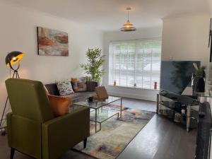 a living room with a green chair and a couch at Stylish 3 bedroom House In Grt Gregorie Basildon & Essex - Free Wifi, Parking, Dedicated Office & Private Garden in Basildon