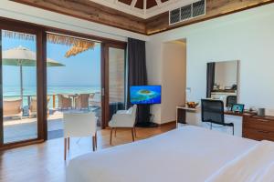 a bedroom with a bed and a view of the ocean at Kandolhu Maldives in Himandhoo 