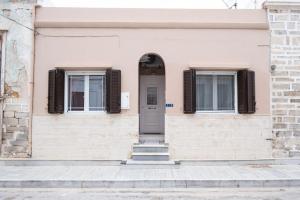 um prédio com uma porta cinza e duas janelas em Aneseas Syros em Hermópolis