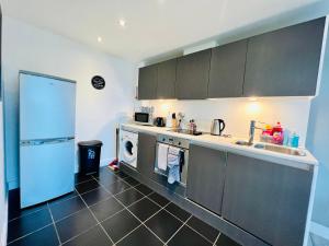 a kitchen with a sink and a washer and dryer at Lush Cardiff Bay Apartment with Secure Parking and Fast Wifi in Cardiff