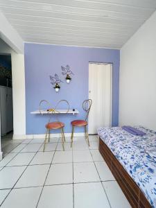 1 dormitorio con 2 sillas y una pared azul en La casita lilás, en Beberibe
