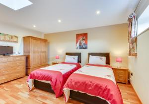 Great PlumsteadにあるOakdeneのベッドルーム1室(赤いシーツとベッド2台、テレビ付)