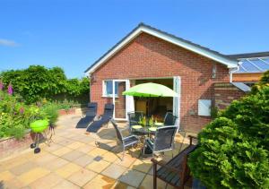 a patio with a table and chairs and an umbrella at Oakdene in Great Plumstead