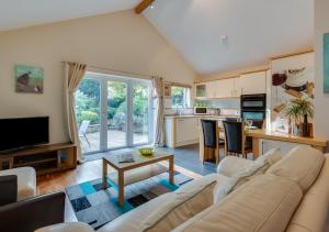 a living room with a couch and a kitchen at Oakdene in Great Plumstead