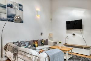 a living room with a couch and a tv at Stunning Award Winning Barn Conversion- 2 Bedroom in London