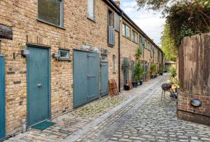 a brick alley with blue doors on a brick building at Stunning Award Winning Barn Conversion- 2 Bedroom in London