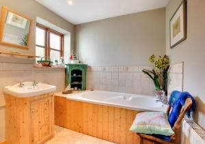 a bathroom with a large tub and a sink at Old Post Office Cottage in Poringland