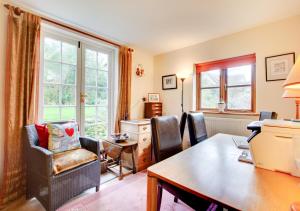 a living room with a desk and chairs and a window at Old Post Office Cottage in Poringland