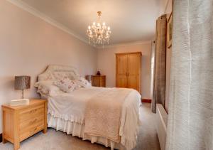 1 dormitorio con cama y lámpara de araña en Nursery Cottage en Clippesby