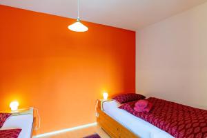 ビューラータールにあるFerienwohnung Fasseのオレンジ色の壁のベッドルーム1室、赤いシーツ付きのベッド1台が備わります。