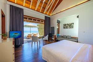 a bedroom with a bed and a living room at Kandolhu Maldives in Himandhoo 