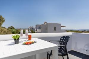 a white table and chair on the balcony of a house at Vino luxury suites in Agia Anna Naxos