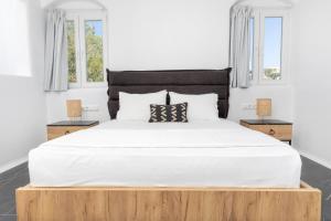 a bedroom with a large white bed with two tables at Vino luxury suites in Agia Anna Naxos