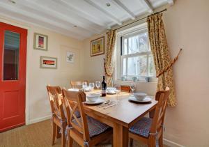 a dining room with a wooden table and a red door at Owl Cottage in Little Walsingham