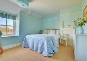 Dormitorio azul con cama y ventana en Owl Cottage en Little Walsingham
