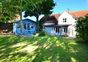 una casa azul y blanca con patio en Owl Cottage en Little Walsingham