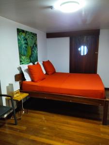 a bedroom with a large bed with orange sheets at LE CHALET DOMAINE DU ROCHER in Bourda