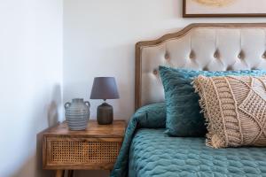a bed with a blue comforter and a lamp on a table at Apartamento Marbella Center III in Marbella +10 photos