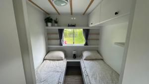 een kleine kamer met 2 bedden en een raam bij PURE - Chalet Zeeland - garden out of sight in Hoek