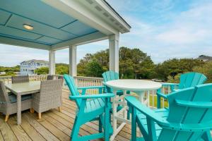 una terraza con sillas azules y una mesa y sillas blancas. en Corolla Vacation Rental with Pool, Walk to Beach!, en Corolla