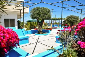 a group of blue benches in a garden with flowers at BELLA CASA KOLYMPIA in Kolymbia