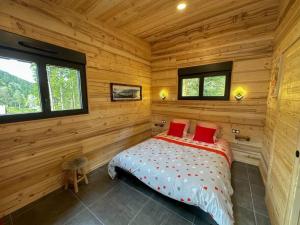 a log cabin bedroom with a bed with red pillows at Le Refuge perché du saut de la bourrique SPA Gérardmer in Gérardmer
