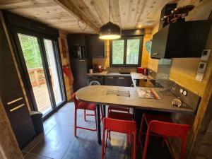 een keuken met een eiland met rode stoelen erin bij Le Refuge perché du saut de la bourrique SPA Gérardmer in Gérardmer