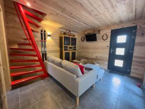 a living room with a couch and a red staircase at Le Refuge perché du saut de la bourrique SPA Gérardmer in Gérardmer