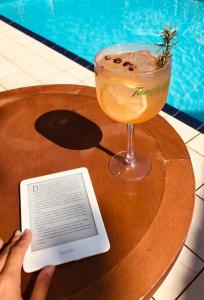 a person holding a book and a drink on a table at Hotel e Pousada Canto Mágico in Maresias