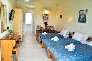 a hotel room with three beds and a table at BELLA CASA KOLYMPIA in Kolimbia