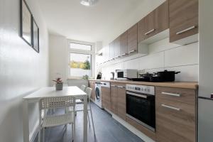 埃森的住宿－T&K Apartments - 1-3 Zimmer Apartments - Essen，厨房配有木制橱柜、桌子和炉灶。