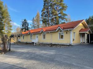 a yellow house with a red roof on a street at Lossirannan Kartano in Huutotöyry