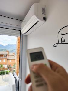 a person holding a remote control in front of a window at Apartamento rural en el Berguedà "Lluis & Antonia" A Ac in Sant Jordi de Cercs +40 photos