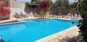 a blue swimming pool with chairs and a fence at Villa Océano with private heated pool, aircon and Seaview in Parque Holandes