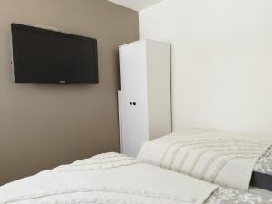 1 Schlafzimmer mit 2 Betten und einem Flachbild-TV an der Wand in der Unterkunft Courtyard Condo Twin in Liepāja